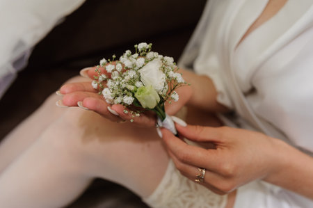 Boutonniere of the groom with white flowers in the hands of the bride. morning of the brideの写真素材