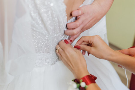 Bridesmaids tie a bow on the wedding dress. Morning of the bride