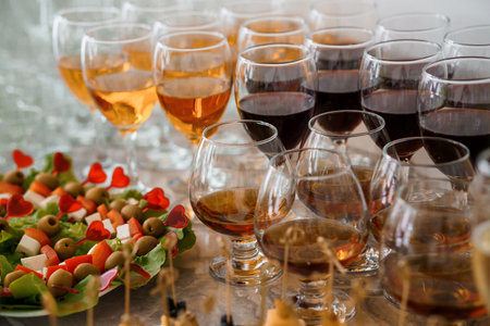 Festive buffet table. Glasses of white champagne, glasses of cognac, red wine. Canape with cheese and olives on a skewerの写真素材
