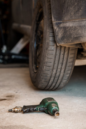 Green pneumatic screwdriver in the garage, with a car in the backgroundの写真素材