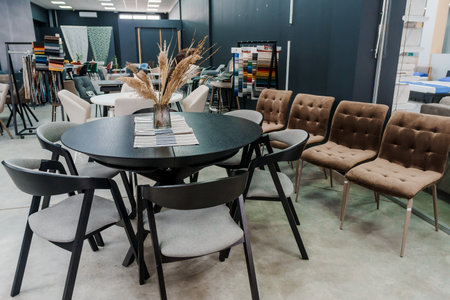 Black wooden table complete with black wooden chairs with soft fabric upholstery. Glass vase on the...