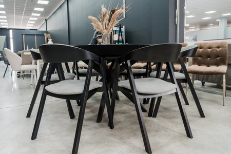 Black wooden table complete with black wooden chairs with soft fabric upholstery. Glass vase on the...
