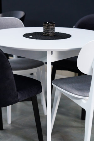 White wooden table combined with black and white wooden chairs with soft fabric upholstery. There is...
