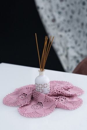 A white wooden table paired with pink wooden chairs with soft fabric upholstery. There is a white...