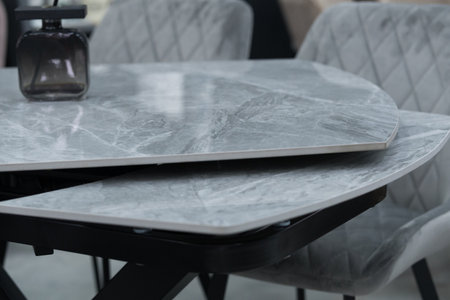 Gray wooden table complete with gray wooden chairs with soft fabric upholstery. Black jar with incense sticks on the tableの写真素材