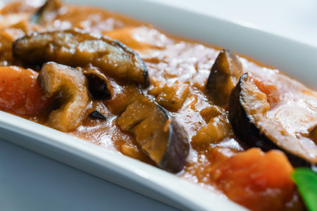Stewed meat with vegetables and mushrooms on a white plate