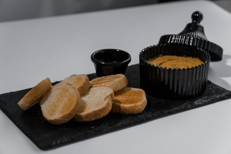Pate with sauce and croutons on a black board