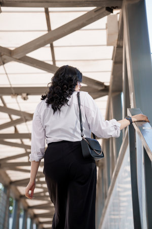 Business woman in black trousers and white shirt. Business lady in a black business suit against the background of a business centerの写真素材