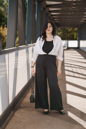 Confident Woman in Chic Black and White Attire on Urban Bridge.