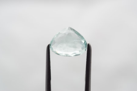 Glistening Aquamarine Gemstone Held by Precision Tweezers on Soft Background.の写真素材