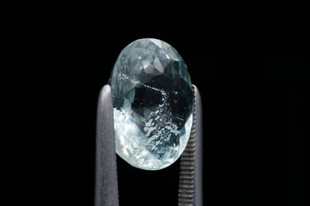 Exquisite Close-Up of a Faceted Aquamarine Gemstone in Professional Jewelry Tweezers.の写真素材