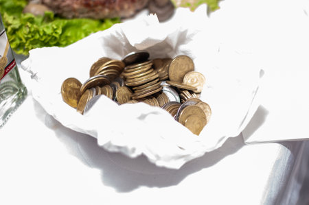 Gleaming Coins Resting in a White Cloth Pouch with Fresh Ingredients in Background.の写真素材