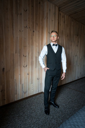 Elegantly Dressed Man in Stylish Vest with Modern Wooden Interior Background.の写真素材