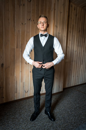Sophisticated Gentleman in Elegant Formal Attire Standing Against Rustic Wooden Backdrop.の写真素材