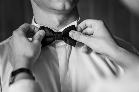 Elegant Preparations: Hands Perfectly Adjusting a Classic Bow Tie in Black and White.の写真素材