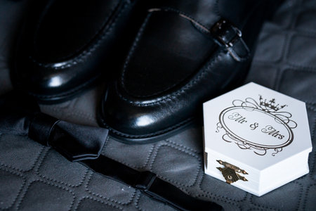 Elegant Wedding Essentials: Black Leather Shoes, Bow Tie, and Decorative Mr. Mrs. Box on Quilted...