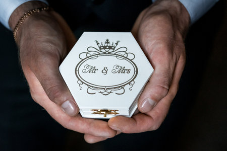 Elegant Hands Holding Mr & Mrs Bridal Ring Box with Intricate Crown Design