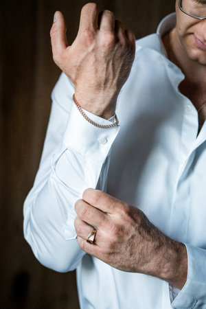 Elegant Focus: Man Adjusting Cufflinks in a Crisp White Shirt.