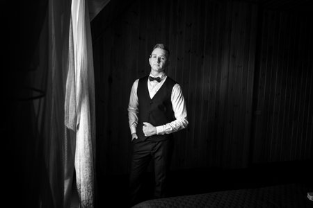 Elegant Portrait of a Man in Formal Attire with Dramatic Lighting in a Wooden Interior.の写真素材