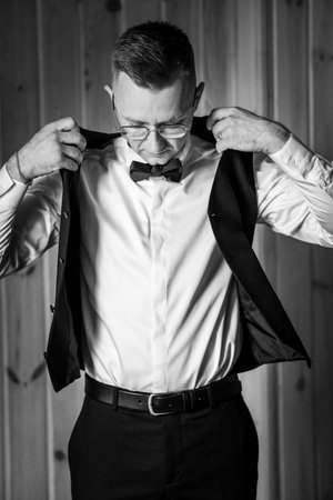 Elegant Preparation: A Man Adjusting His Suit Jacket in Classic Black and White.の写真素材