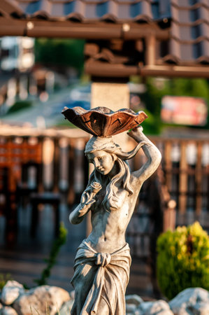 Elegant Stone Sculpture of a Woman in a Sunlit Garden Setting.の写真素材