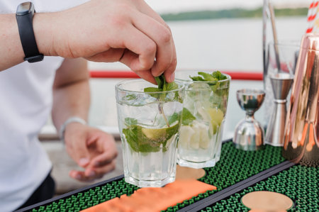 Refreshing Mint Mojito Preparation at a Relaxing Outdoor Bar with Scenic Waterfront View.の写真素材