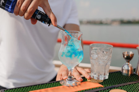 Refreshing Blue Cocktail Being Poured at a Sunny Outdoor Bar Setting.