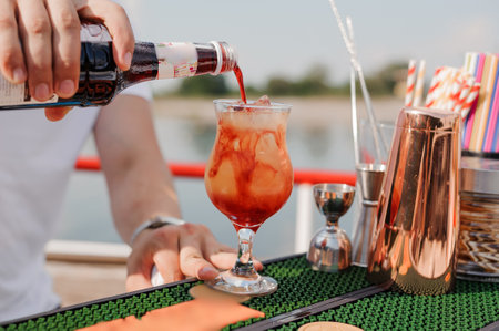 Refreshing Summer Cocktail Being Poured Over Ice with Vibrant Colors and Bokeh Background.