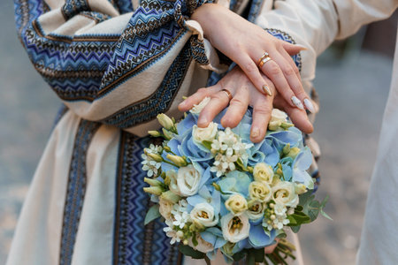 Romantic Close-Up of Elegant Hands Holding a Beautiful Blue and White Floral Bouquet with Delicate Rings.の写真素材