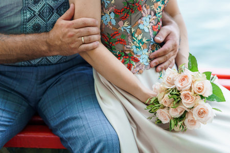 Romantic Embrace: A Close-Up of a Bride and Groom with a Stunning Floral Bouquet Near Water.