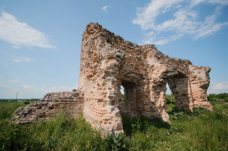 Abandoned Stone Ruins Surrounded by Lush Greenery Under a Clear Blue Sky.の写真素材