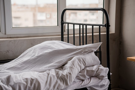 Tranquil Morning in a Minimalist Bedroom with Unmade Bed and Soft Light Filtering Through Window.の写真素材