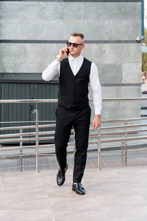 Elegantly Dressed Businessman Walking with Confidence in Urban Setting.