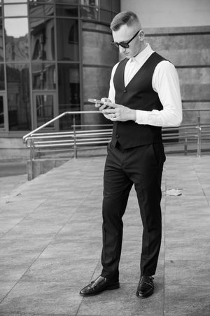 Elegant Businessman in Chic Urban Setting Checking His Smartphone.の写真素材