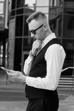 Thoughtful Elegance: A Dapper Man in Formal Attire Engaged with His Phone.の写真素材