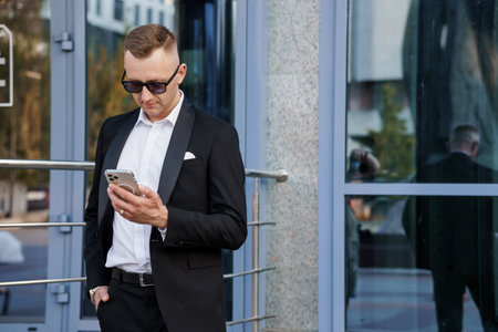 Sleek Urban Professional in Modern Attire Engaging with Smartphone Outside a Contemporary Building.