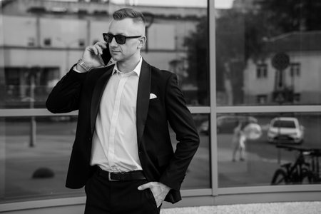 Confident Businessman in Stylish Suit and Sunglasses Engaged in Phone Conversation.の写真素材