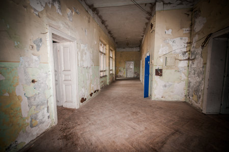 Haunting Corridor of a Timeworn Building with Flaking Walls and Dim Light.の写真素材
