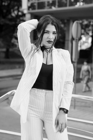 Stylish Young Woman in Striped Suit Posing Confidently in Urban Environment.