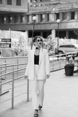 Stylish Businesswoman in Striped Suit Strolling Urban Walkway.の写真素材