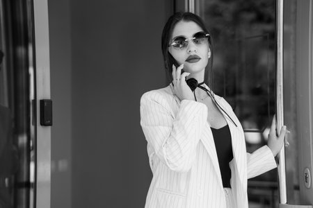 A Confident Businesswoman in a Stylish Pinstripe Suit Engaging on Her Smartphone.の写真素材