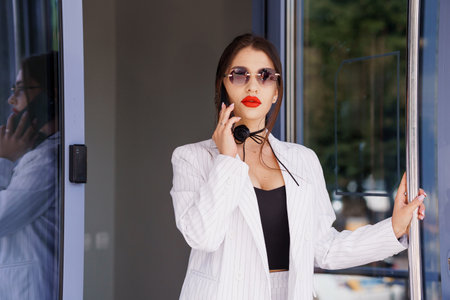 Stylish Businesswoman in Chic Striped Suit with Bold Red Lipstick and Sunglasses.の写真素材