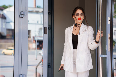 Stylish Businesswoman in Striped Suit Exiting Modern Office Space.の写真素材