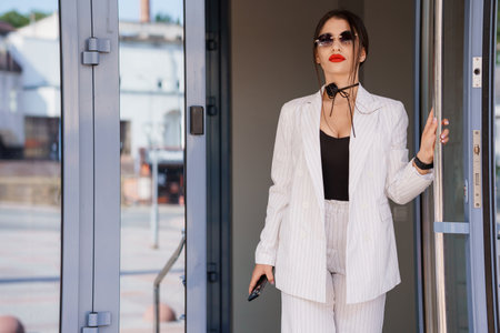 Stylish Businesswoman Exiting Modern Office on a Sunny Day.の写真素材