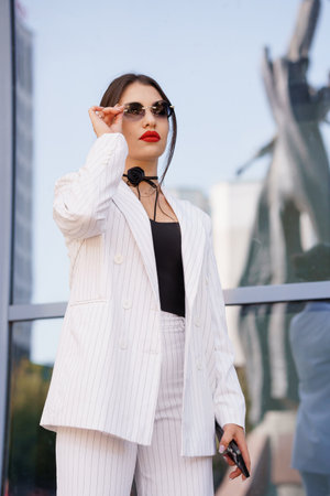 Stylish Young Woman in Pinstripped Suit Posing Outside Modern Building.の写真素材