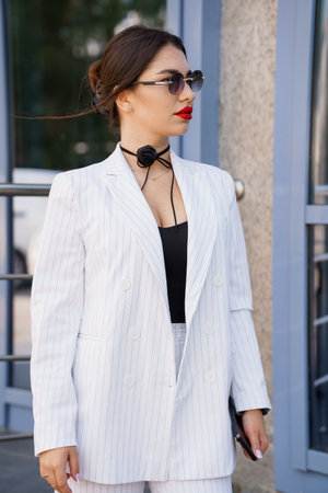 Elegant Chic Woman in Striped Suit with Sunglasses and Bold Lipstick.の写真素材