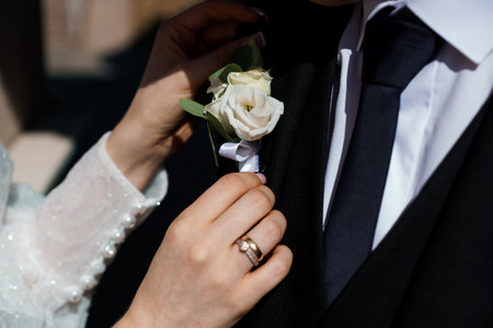 Elegant Wedding Moment: Bride Attaching Boutonniere to Groom's Lapel.