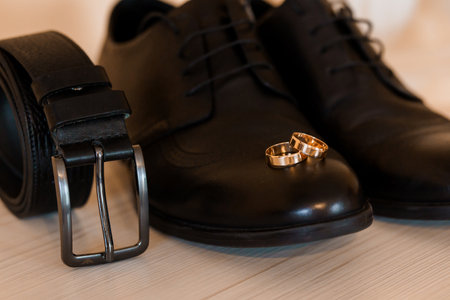 Elegant Wedding Attire Display Featuring Formal Shoes, Gold Rings, and a Sleek Belt.