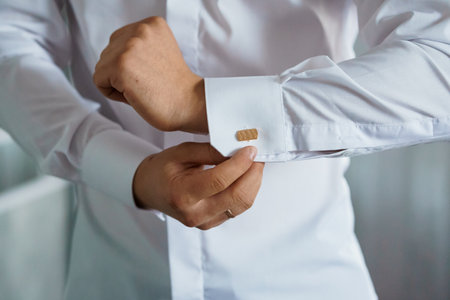 A Well-Dressed Man Adjusting His Cufflink on a White Shirt.