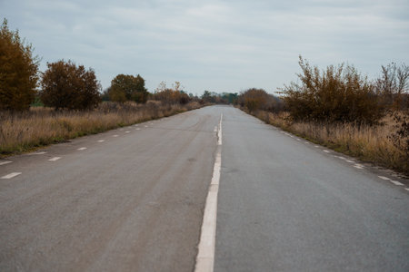 Abandoned Road Stretching Into the Distance Surrounded by Autumnal Foliage.の写真素材